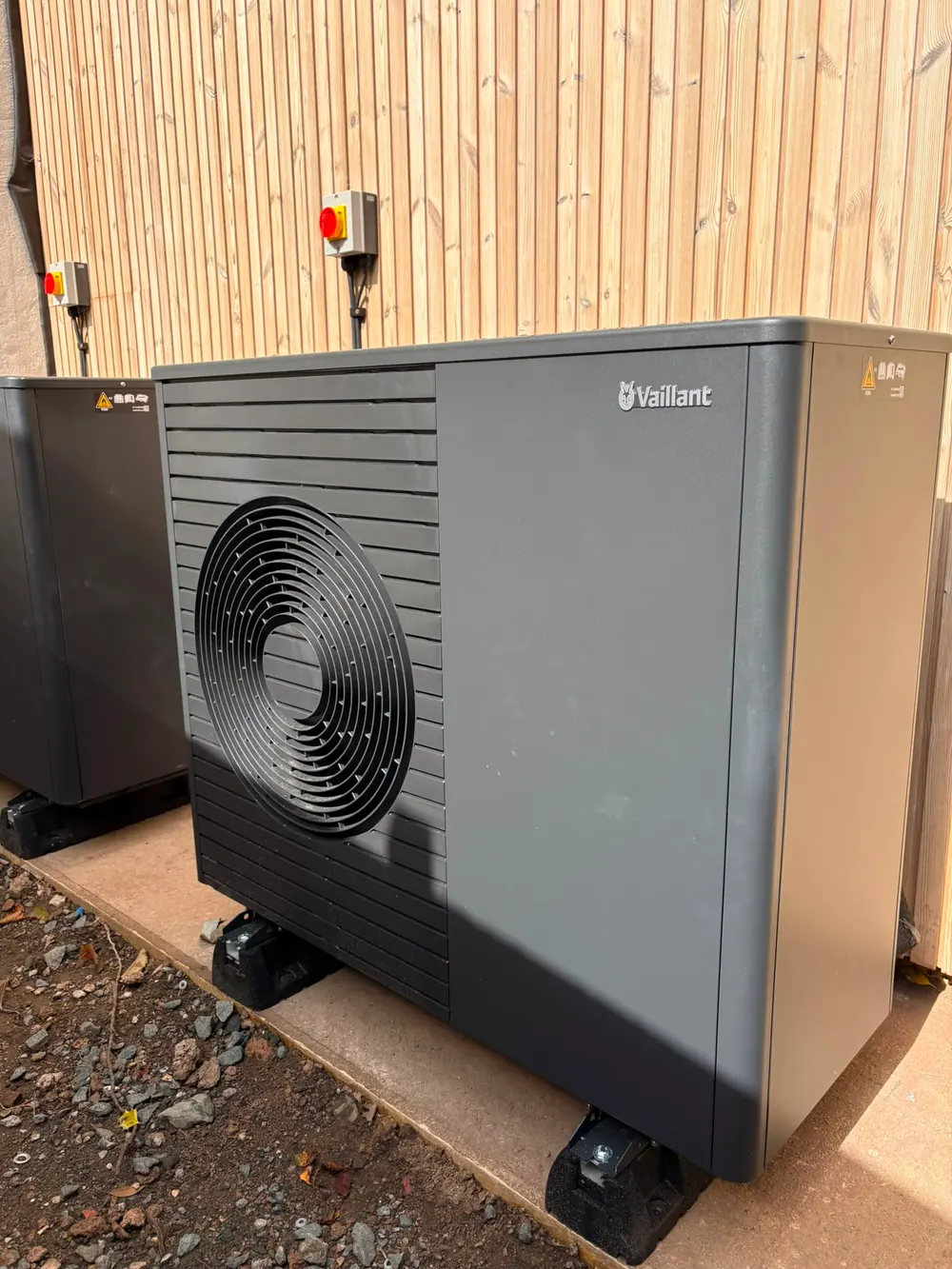 Vaillant air source heat pump installed on a plinth against a timber-clad wall