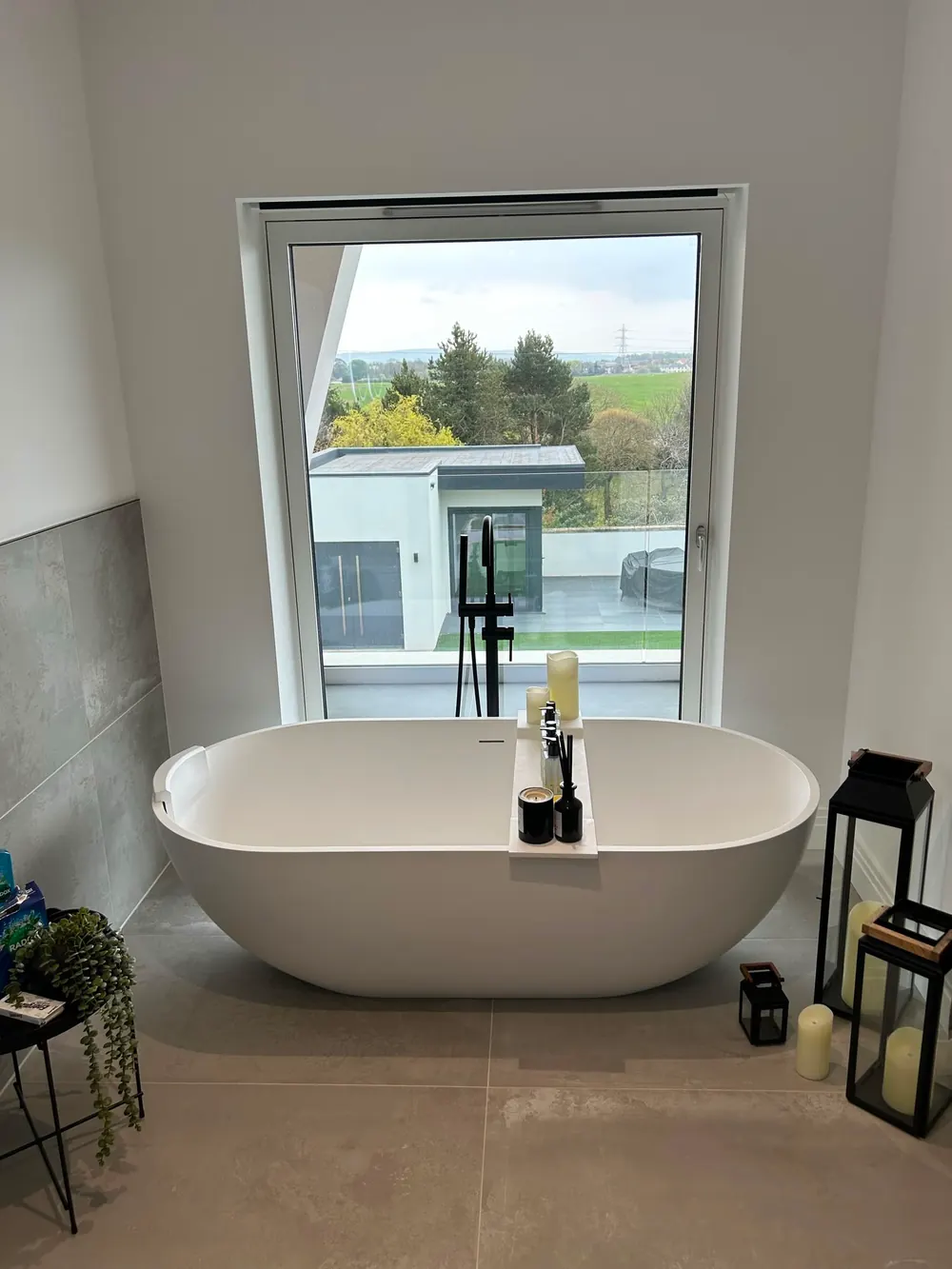 Freestanding bath set in front of a full-height picture window looking out over open countryside