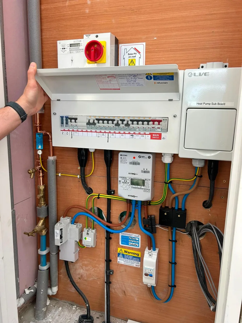 Consumer unit with a heat pump sub-board, generation meter and solar PV isolator on a plywood board