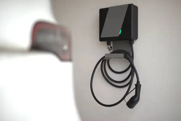 Tethered home EV charge point mounted on a garage wall with the cable coiled