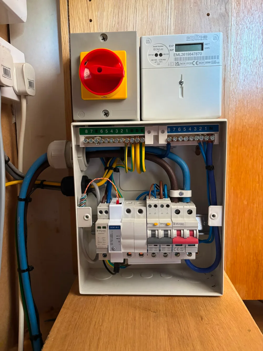 Compact consumer unit wired out with surge protection and RCBOs, beside the meter and isolator