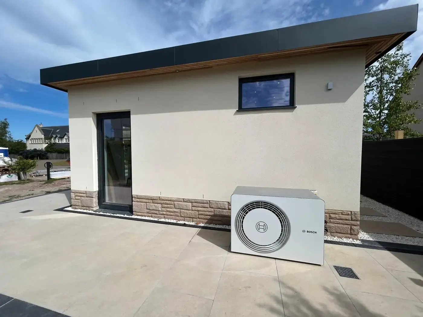 Bosch air source heat pump unit sited on a patio beside a modern single-storey home