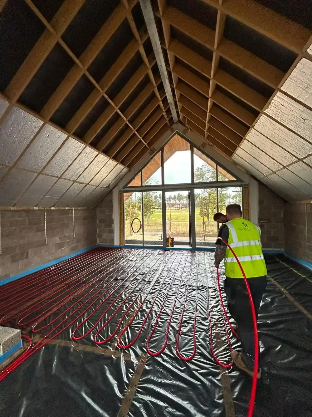 Culbertson engineer laying underfloor heating loops in a vaulted timber-roofed room