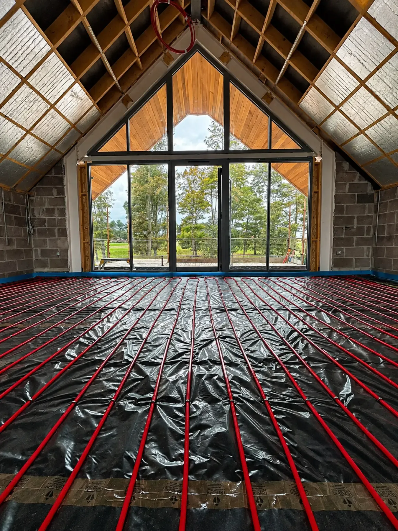 Underfloor heating pipework run out across a vaulted room ahead of screeding